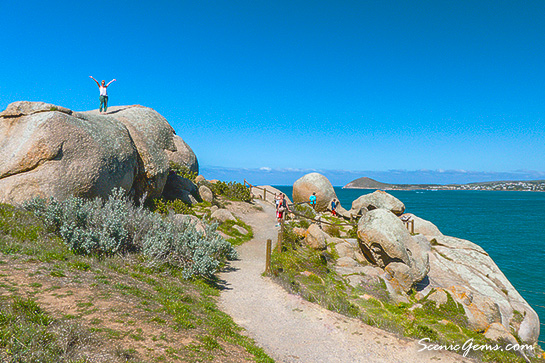 Woman standing ontop of a large granite boulder. Granite Island, Victor Harbour, South Australia